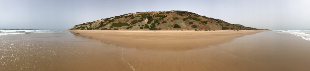Panoramic view of wet golden sandy beach with an island-like in the middle