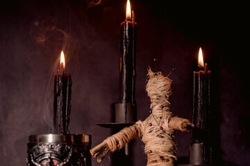 Scary voodoo doll with black candles. Mystic background with ritual esoteric objects, occult and...