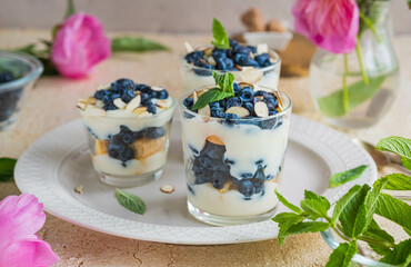 Layered dessert in a glass with custard, biscuits and fresh honeysuckle, garnished with almond...