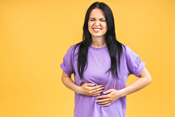Young beautiful woman having abdominal pain isolated on yellow background. - 512681641