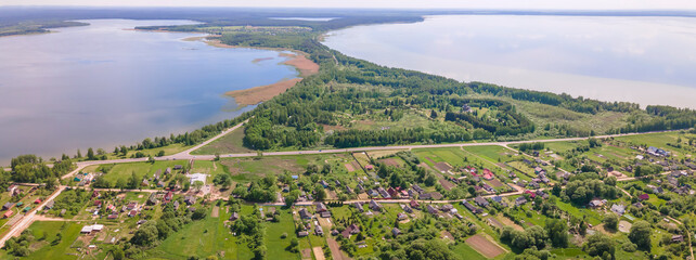 Fototapeta premium Aerial view of lake and small village. Village near the lake. Aerial view of the village and trees on the shore of lake.