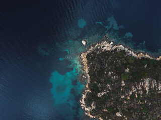 Fototapeta na wymiar Drone view above small island with green vegetation and rocky coastline in the Mediterranean at Chalkidiki peninsula, Greece.