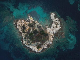 Drone view above small rocky island with green vegetation in the Mediterranean at Chalkidiki peninsula, Greece