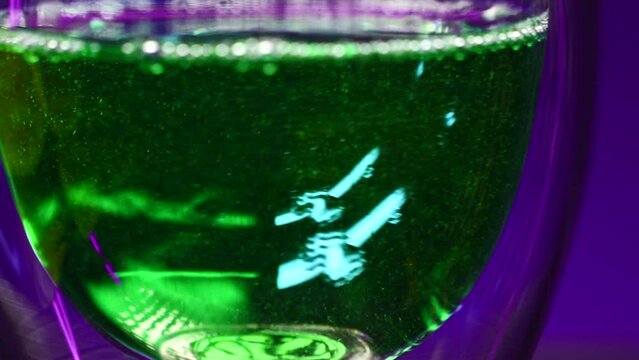 Close-up of green drink in glass. Stock clip. Bright green drink with alcohol in night bar. Alcoholic beverages in bars and clubs