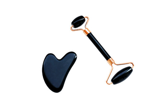 Black gua sha stone and roller for facial massage, horizontal photo on white background. Scraper for Chinese traditional massage, beauty procedure, skin care