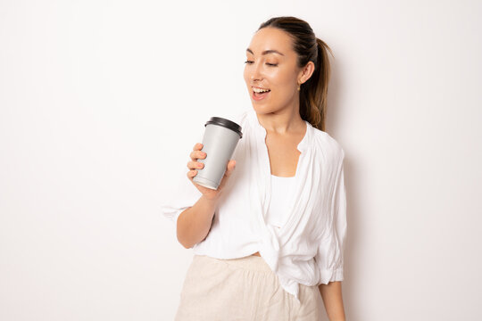Image of young secretary woman wearing white casual shirt drinking coffee from paper cup in the office standing isolated over white background