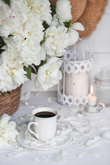 Obraz na płótnie Canvas A beautiful postcard. A white coffee cup with a saucer, candles and a vase with a bouquet of white peonies. Beautiful still life. Spring, summer time. The concept of 