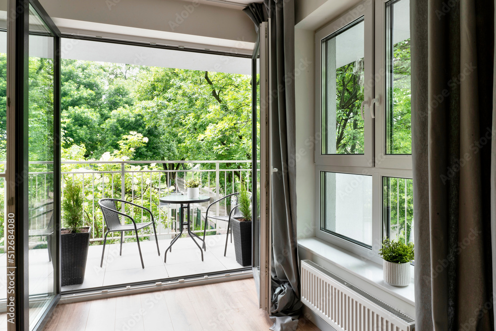 Wall mural big balcony window in new apartment with beautiful view on green nature and table with chairs. moder