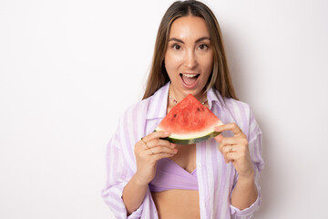 bikini Woman leaning against white background holding watermelon up to mouth