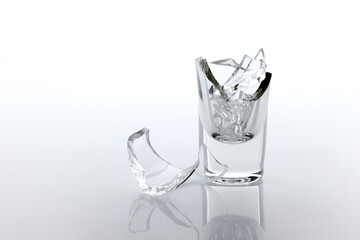 Shards of broken glass goblet and reflection on white background.