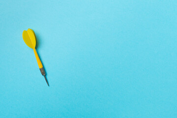 Yellow dart on color background, top view