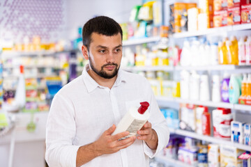 Positive man carefully studying the instructions on a bottle of disinfectant