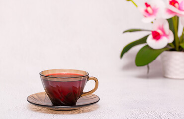 Fototapeta na wymiar Flower tea karkade. Delicious herbal tropical drink on a bright table. A cup of pink tea from dry hibiscus petals, a natural medicinal drink against the background of fern leaves. Tropical morning.