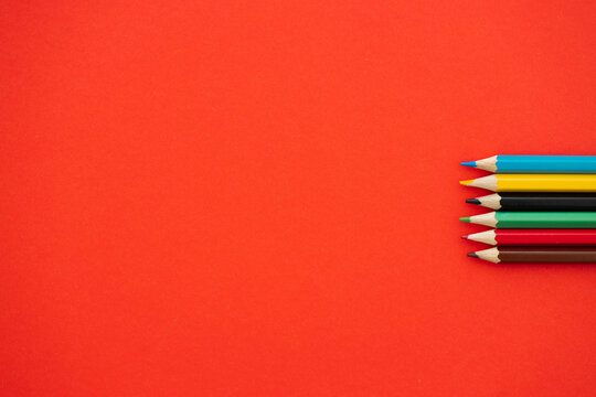 Top view of colorful pencils on red background