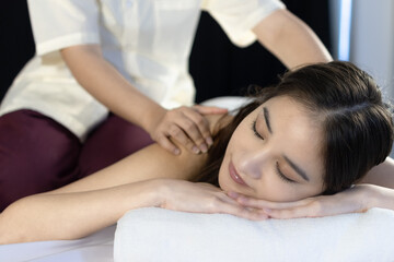 beautiful young Asian woman relaxing during back massage at the spa