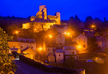 Night view of illuminated fortified Chateau de Belcastel rising above medieval Belcastel village in...