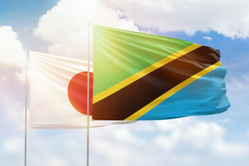 Sunny blue sky and flags of tanzania and japan