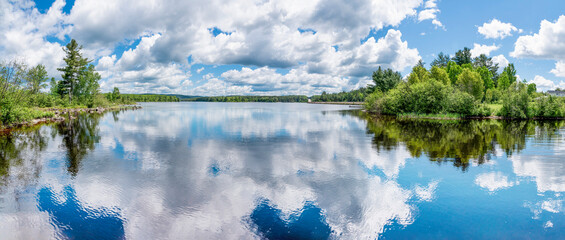 Clouds reflect in the clear blue water of the Ottawa River in this panoramic view taken from Deux...