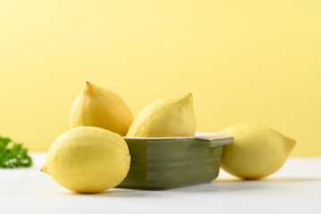 Lemon fruit in green bowl on white and yellow, Citrus fruit