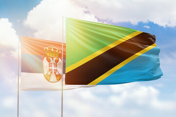 Sunny blue sky and flags of tanzania and serbia