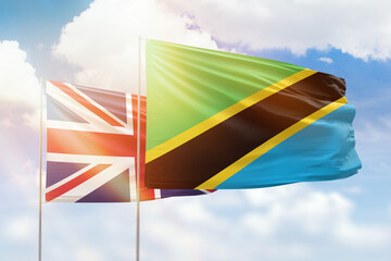 Sunny blue sky and flags of tanzania and united kingdom