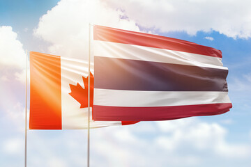 Sunny blue sky and flags of thailand and canada