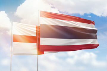 Sunny blue sky and flags of thailand and england