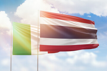 Sunny blue sky and flags of thailand and italy