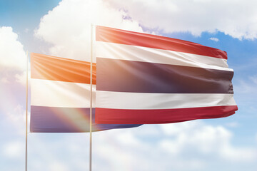 Sunny blue sky and flags of thailand and netherlands