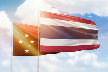 Sunny blue sky and flags of thailand and papua new guinea