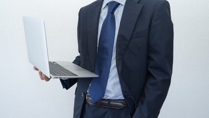 ノートパソコンを手に持つスーツ姿の男性