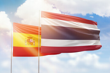 Sunny blue sky and flags of thailand and spain