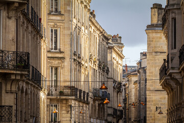 Fototapeta na wymiar Facade of medieval buildings in a dark street, narrow, in the city center of Bordeaux, France. These buildings are typical of the Southwestern French architecture.....