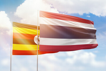 Sunny blue sky and flags of thailand and uganda
