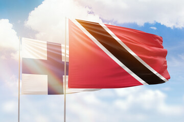 Sunny blue sky and flags of trinidad and tobago and finland