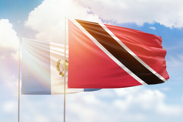 Sunny blue sky and flags of trinidad and tobago and guatemala