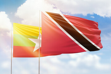 Sunny blue sky and flags of trinidad and tobago and myanmar