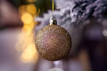 Yellow gold glitter Christmas tree glass ball bauble decoration, golden bokeh, snowy background