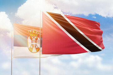 Sunny blue sky and flags of trinidad and tobago and serbia