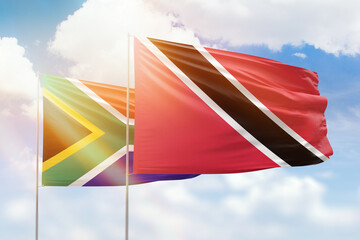 Sunny blue sky and flags of trinidad and tobago and south africa