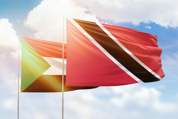 Sunny blue sky and flags of trinidad and tobago and sudan