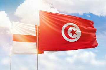 Sunny blue sky and flags of tunisia and england
