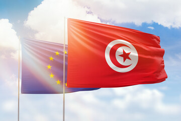 Sunny blue sky and flags of tunisia and european union