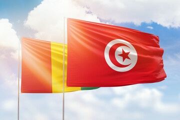 Sunny blue sky and flags of tunisia and guinea