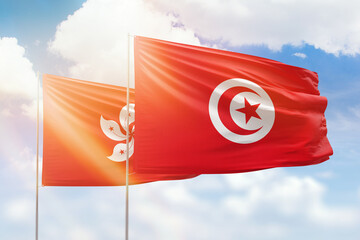 Sunny blue sky and flags of tunisia and hong kong