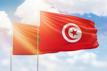 Sunny blue sky and flags of tunisia and morocco
