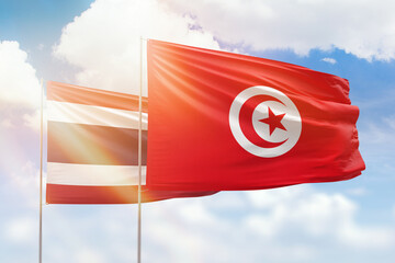 Sunny blue sky and flags of tunisia and thailand