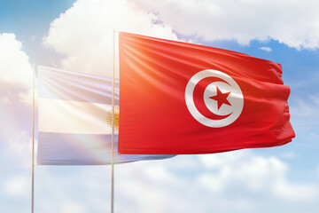 Sunny blue sky and flags of tunisia and argentina