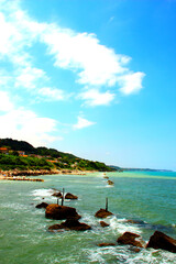 Fresh panorama of the Trabocchi Coast on the Adriatic Sea with huge swathes of green land immersing into the peaceful cyan sea and frothing white waters washing some rocks on a perfect summer day