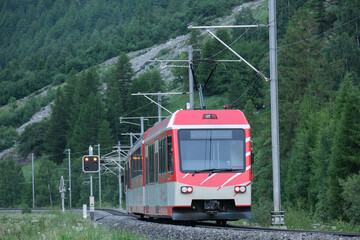 Selective focus picture with motion blur and noise effect of red train at the railway from Zermatt.